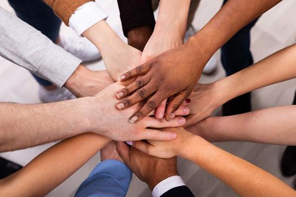 a diverse group of people whose hands are on top of one another in a circle
