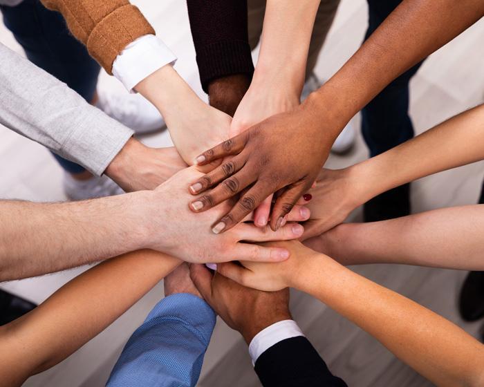 a diverse group of people whose hands are on top of one another in a circle